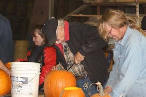 3 adults carving pumpkins for the Pumpkin Hike